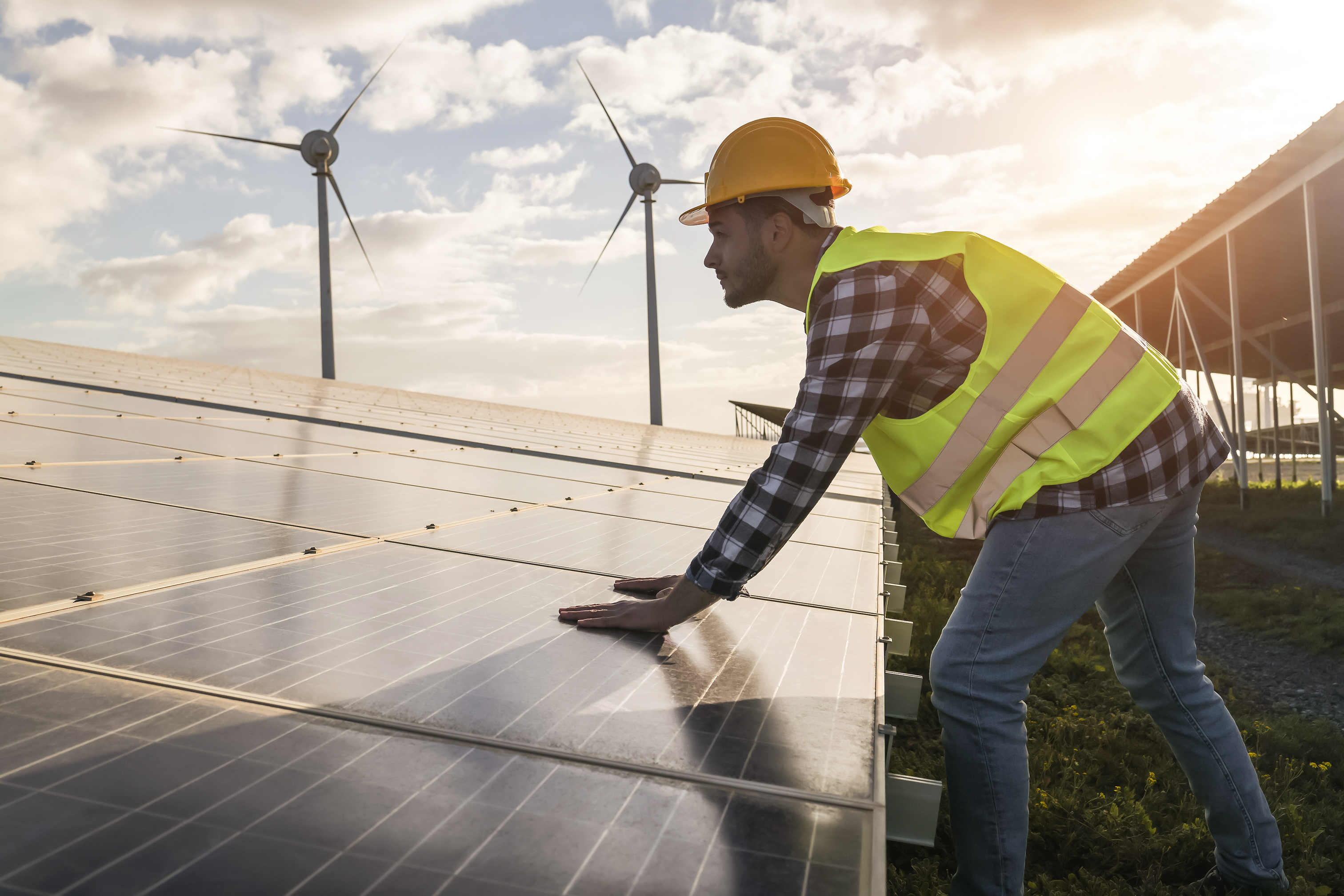 Man working for solar panels and wind turbines - Renewable energy concept - Focus on male worker hands